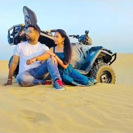 Couple relaxing by a quad bike on the dunes