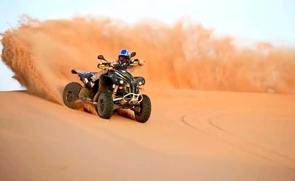 Quad bike kicking up sand on the dunes